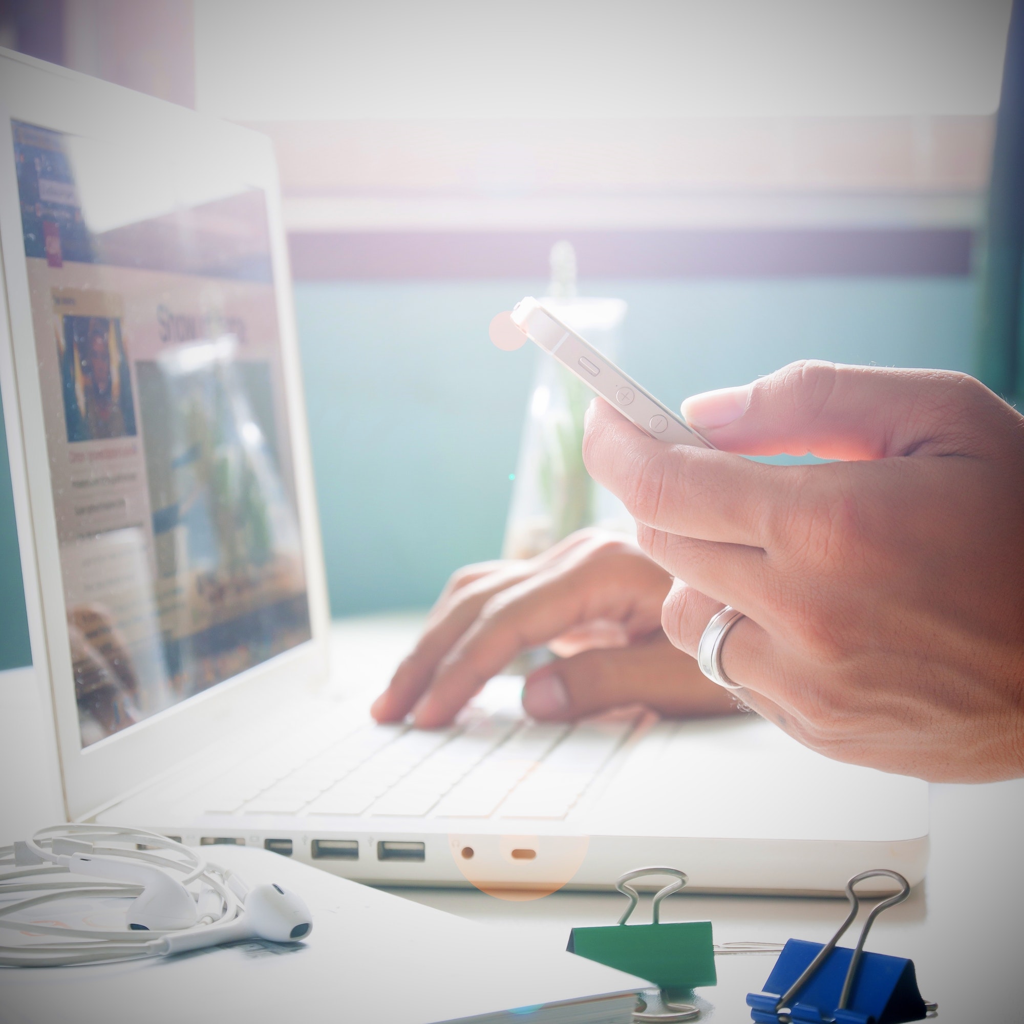 Man's hand holding smartphone and using laptop for online shopping